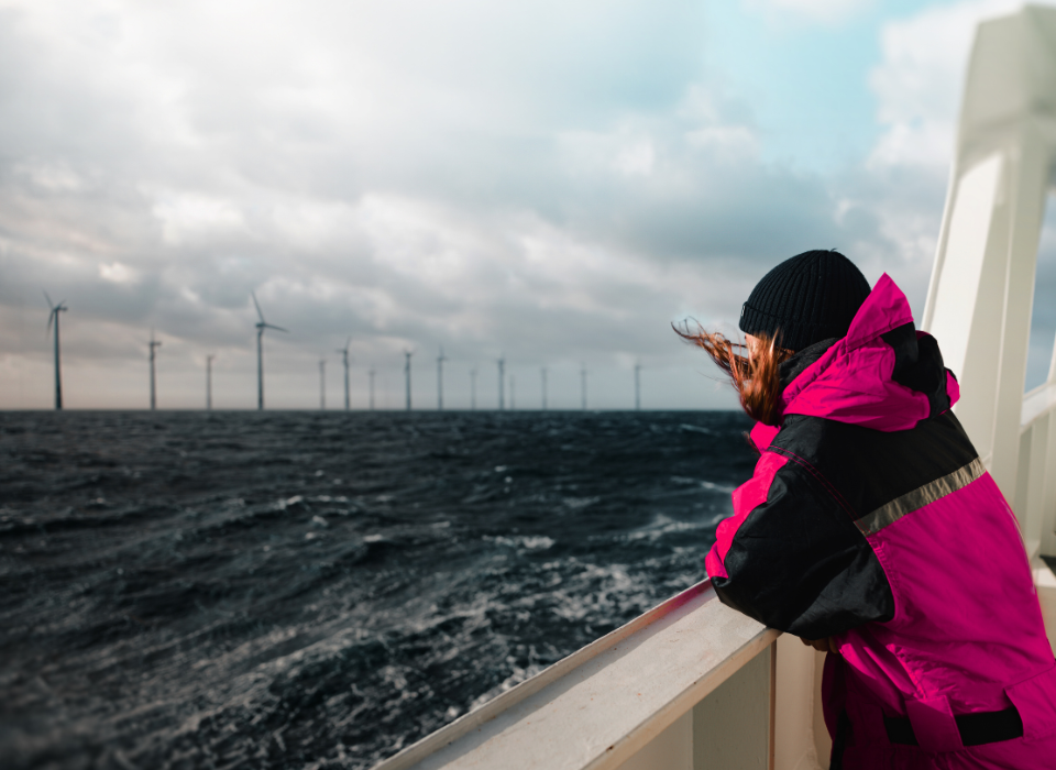 Woman on a boat looking at an offshore wind farm