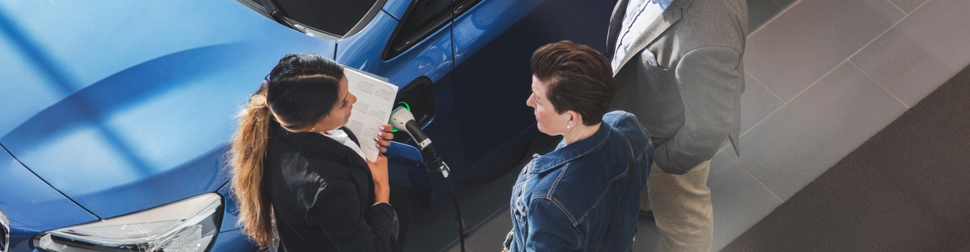 People having a conversation next to an electric car