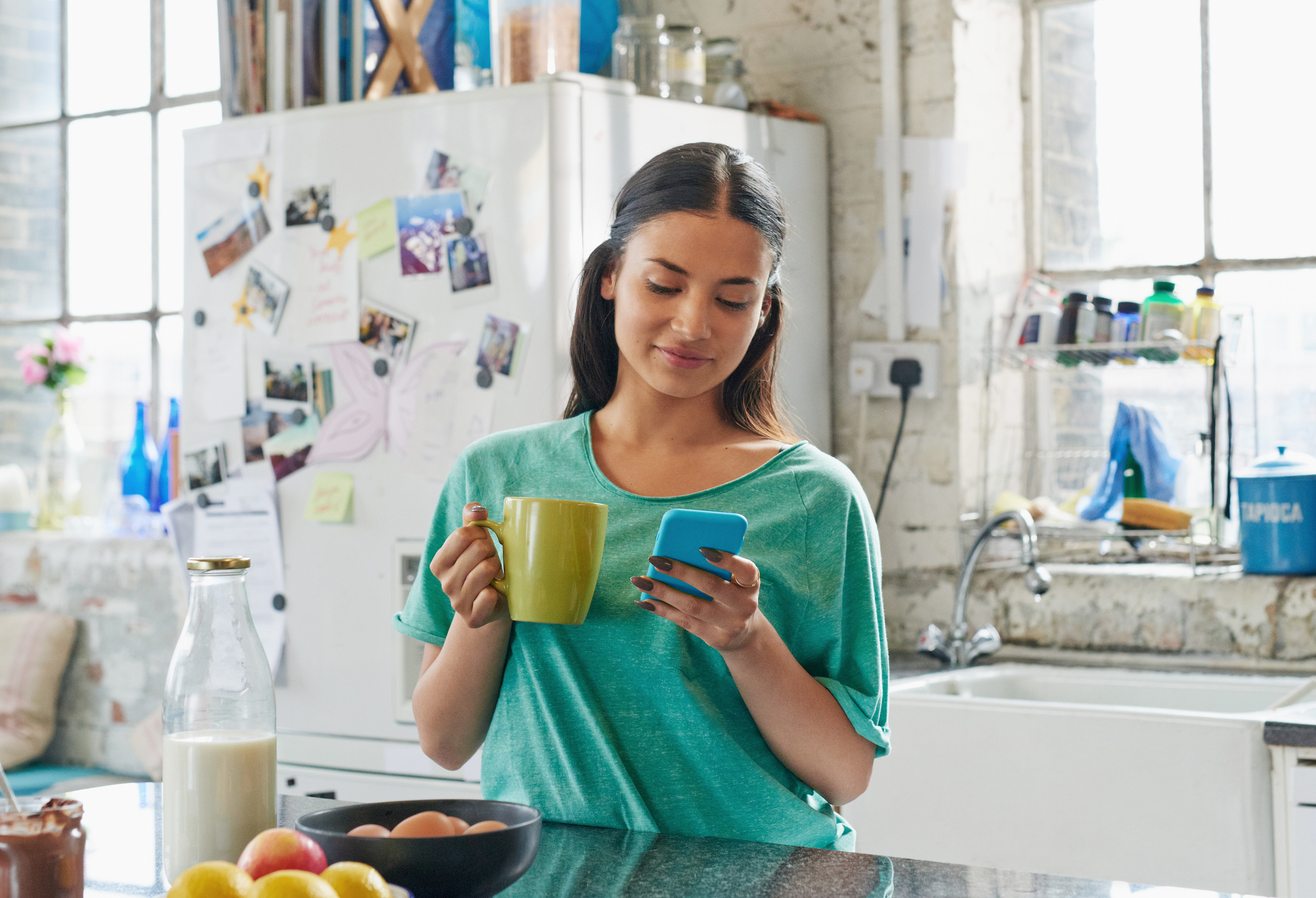 A woman in a kitchen looking at her phone