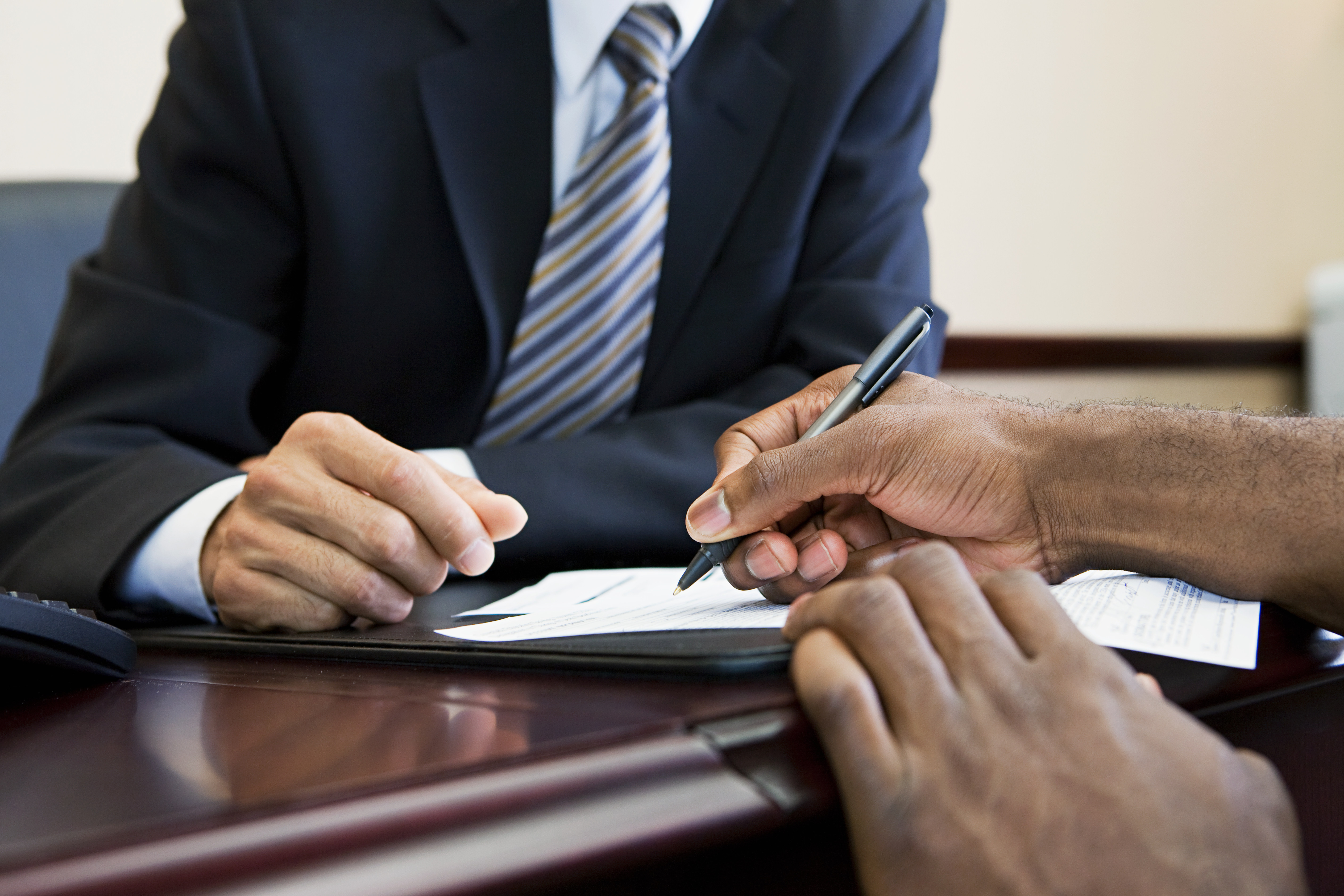 A hand holding a pen signing a document
