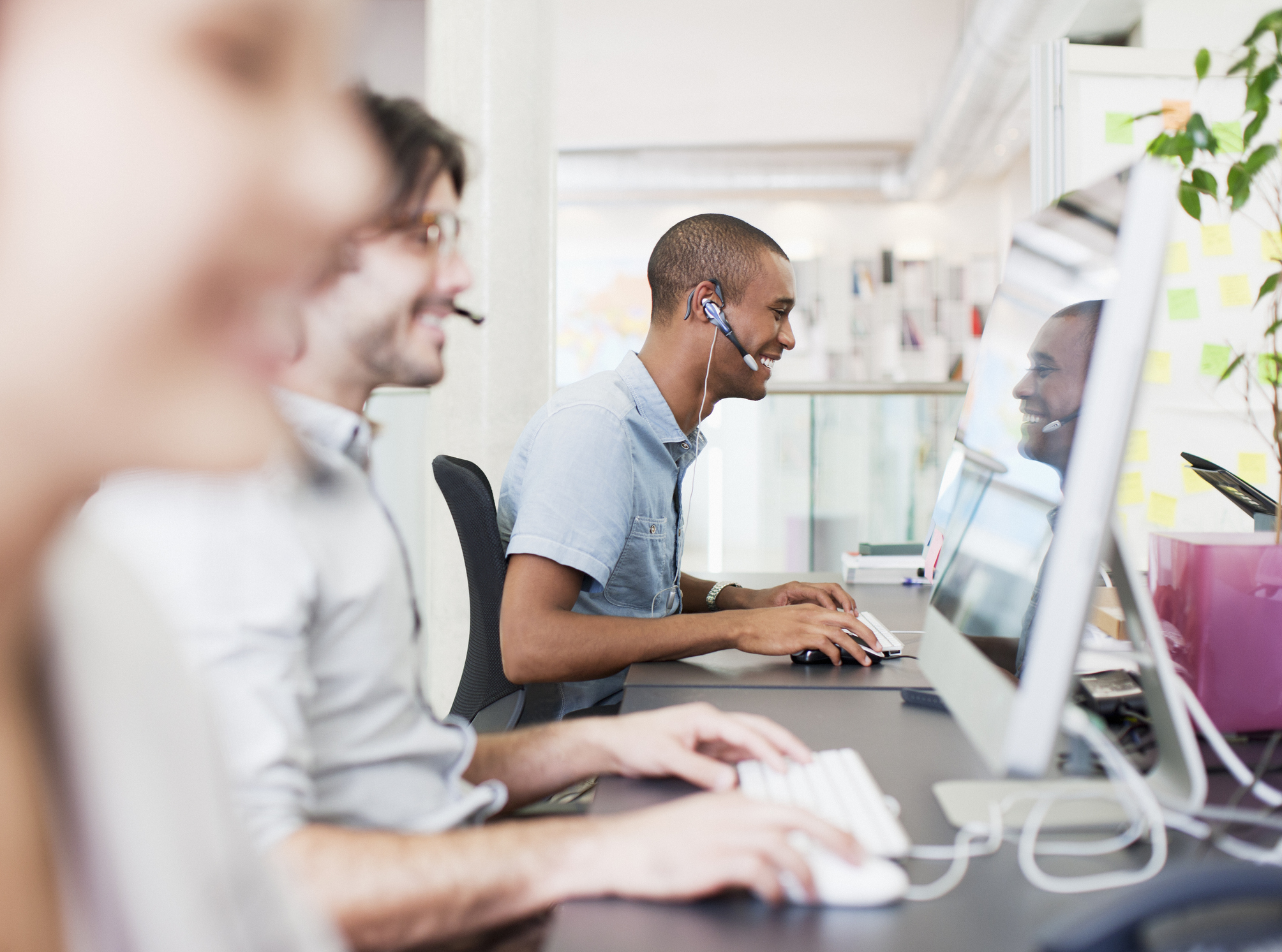 Smiling people wearing headsets working in a call center