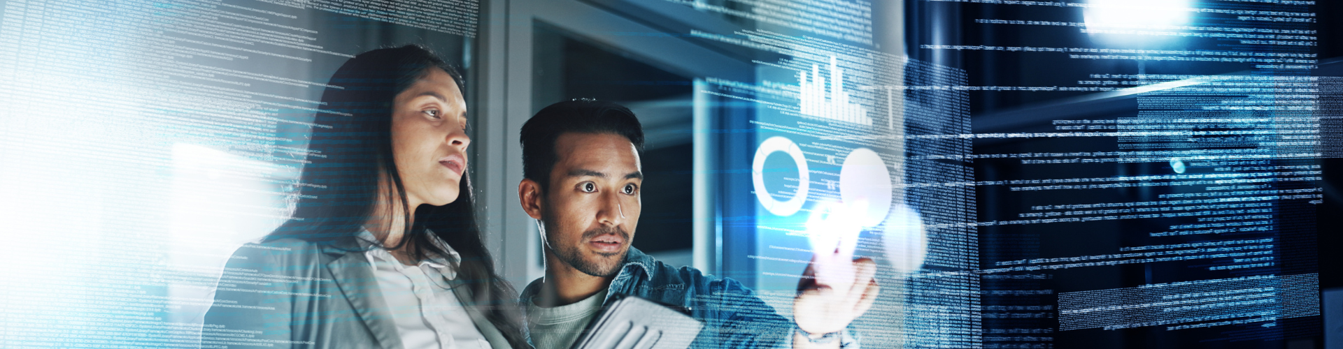 Two people looking at graphs on a transparent screen