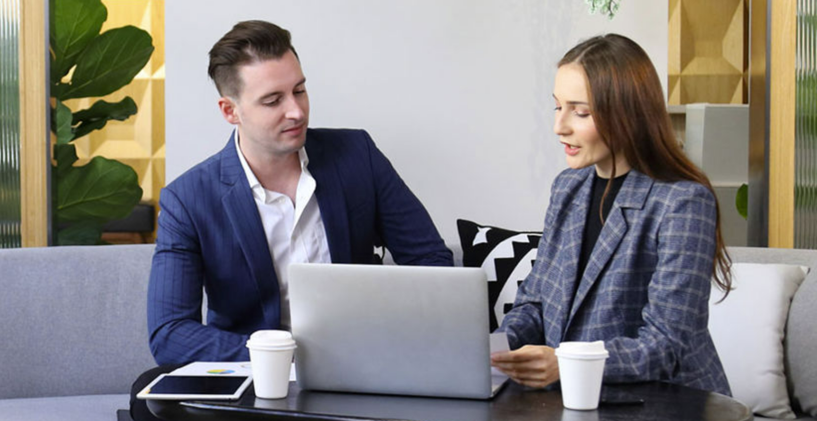 Two people around a laptop in a relaxed office environment