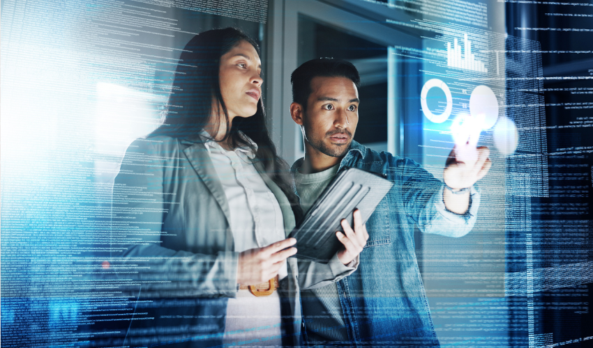 Two people looking at graphs on a transparent screen