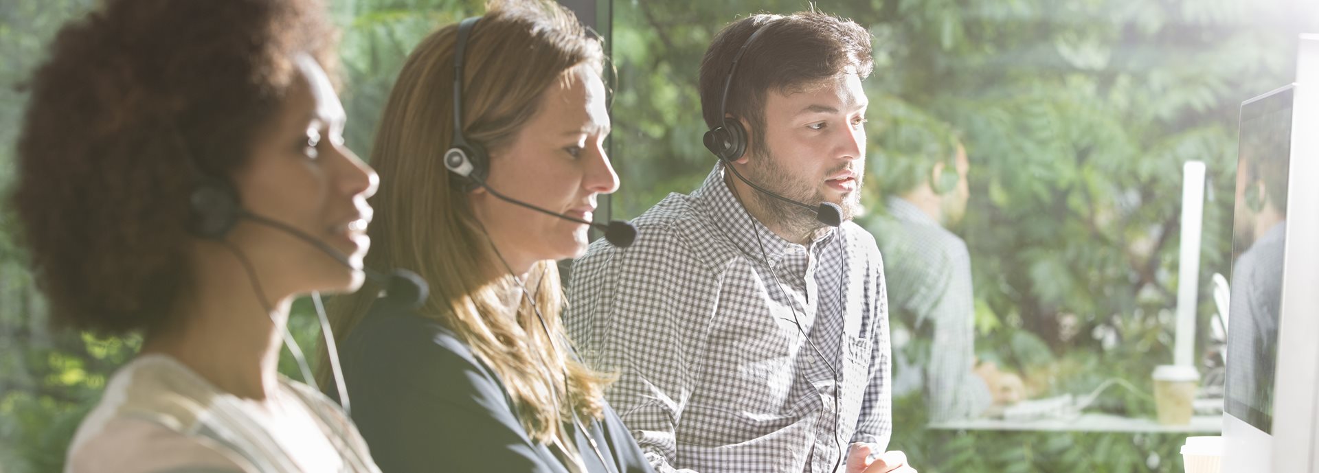 Three colleagues wearing headsets in an office environment