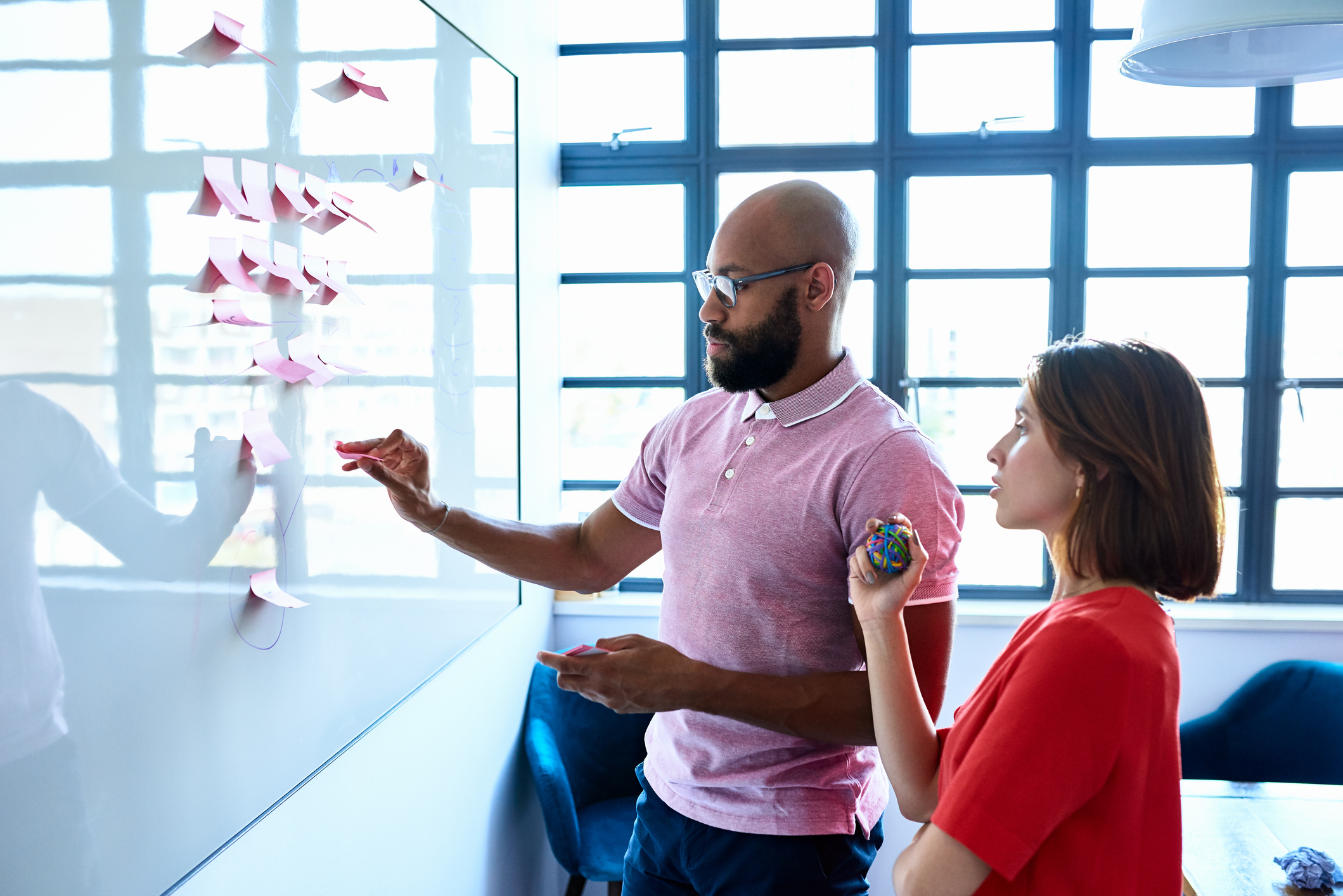 Young woman and male colleague writing ideas on adhesive notes