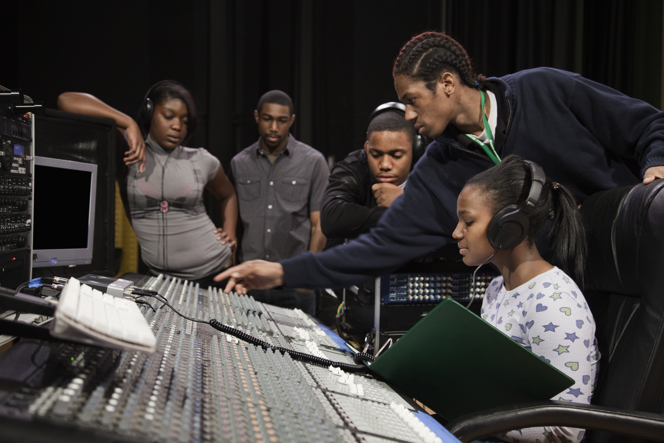 A woman sitting at a recording studio mixing desk