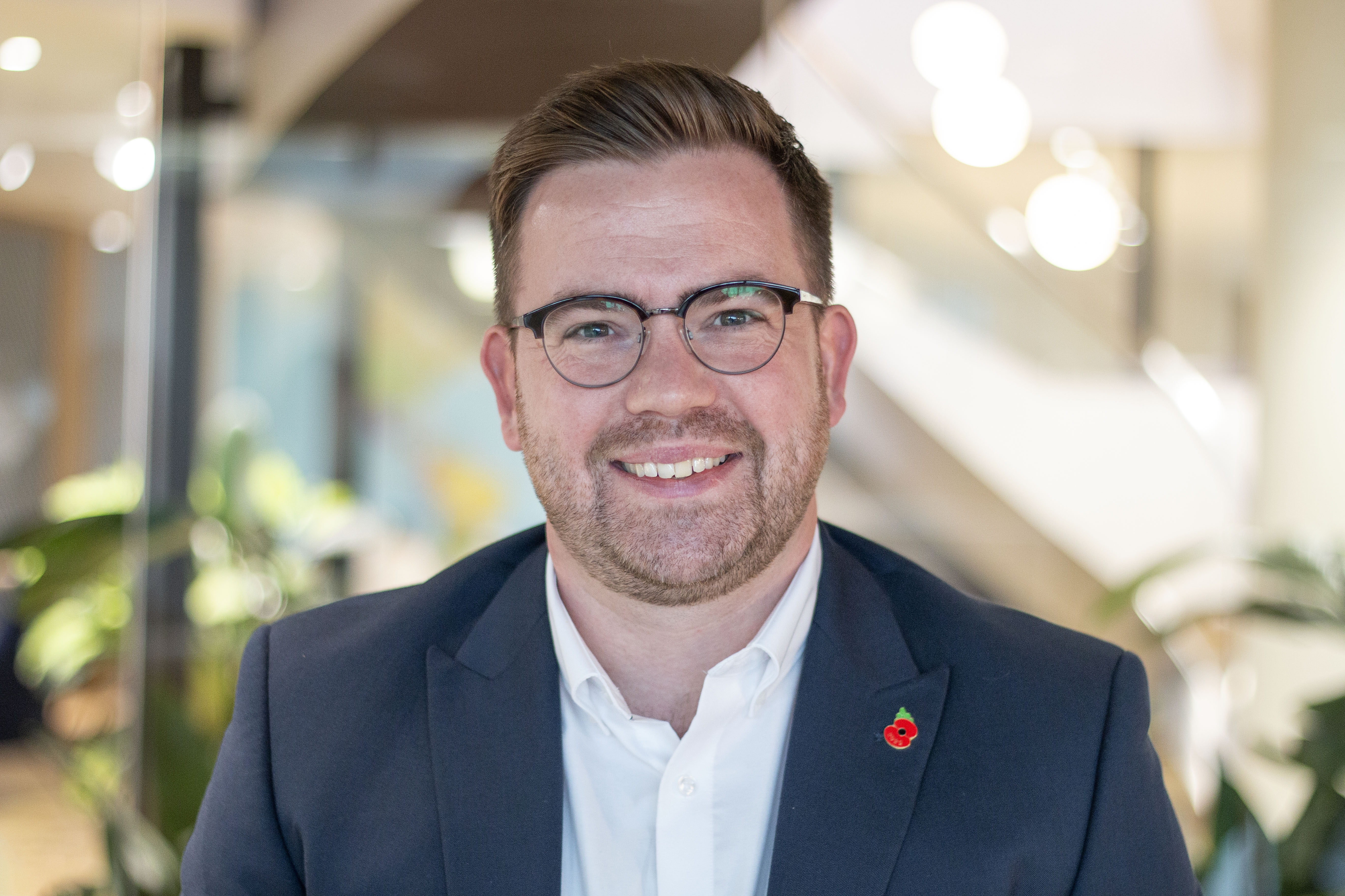 A professional headshot of James Ainsley