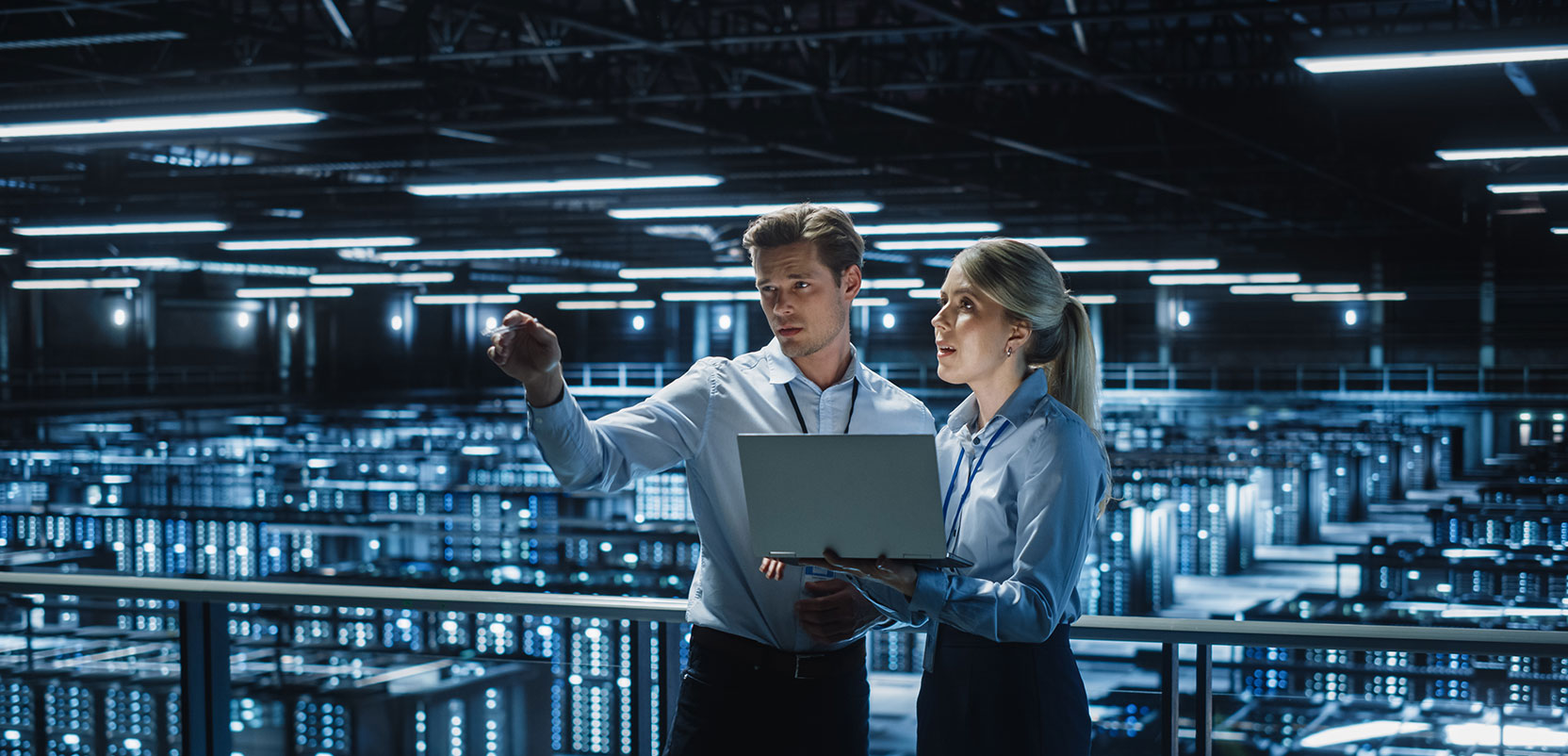 Two colleagues in conversation holding a laptop and standing in a data centre