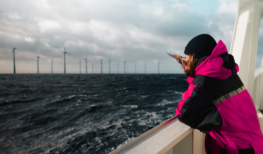 Woman on a boat looking at an offshore wind farm