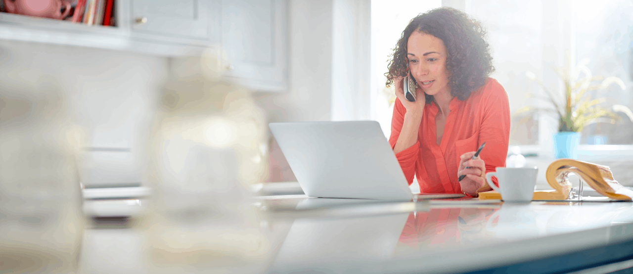 A woman talking on her phone while working on her laptop