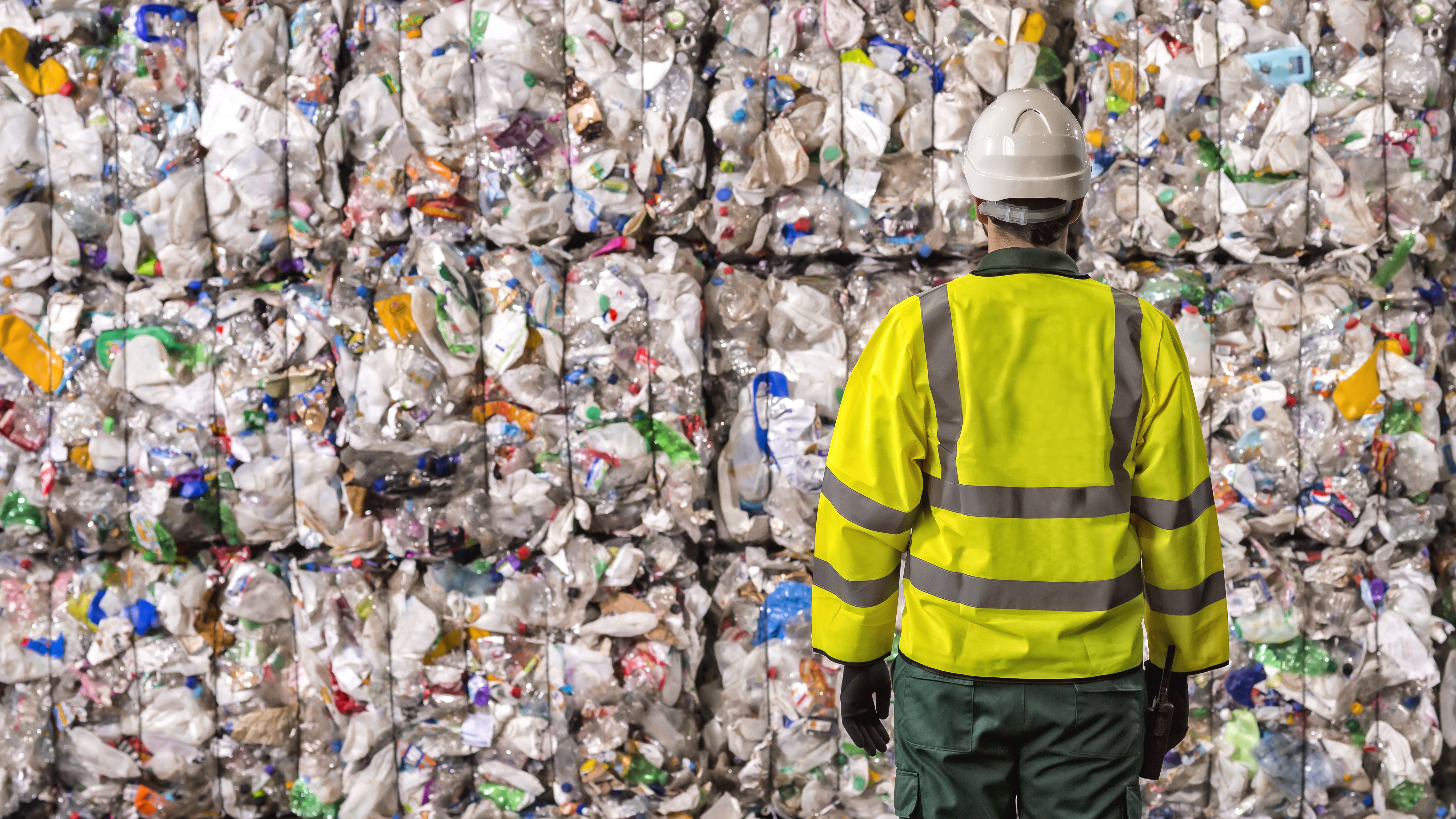 Worker looking at piles of plastic
