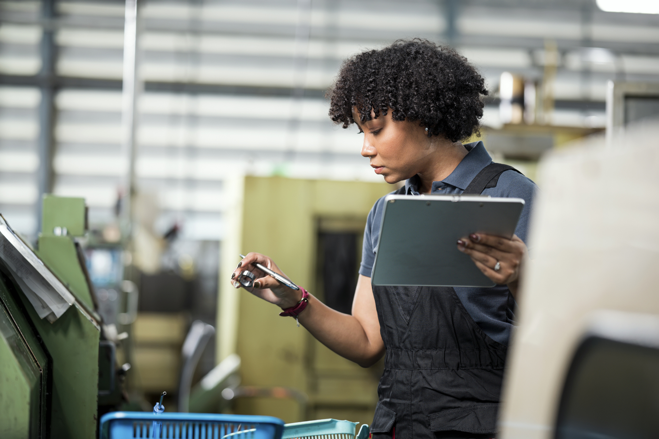 A woman holding a tablet in one hand and a pen and metal ring in the other