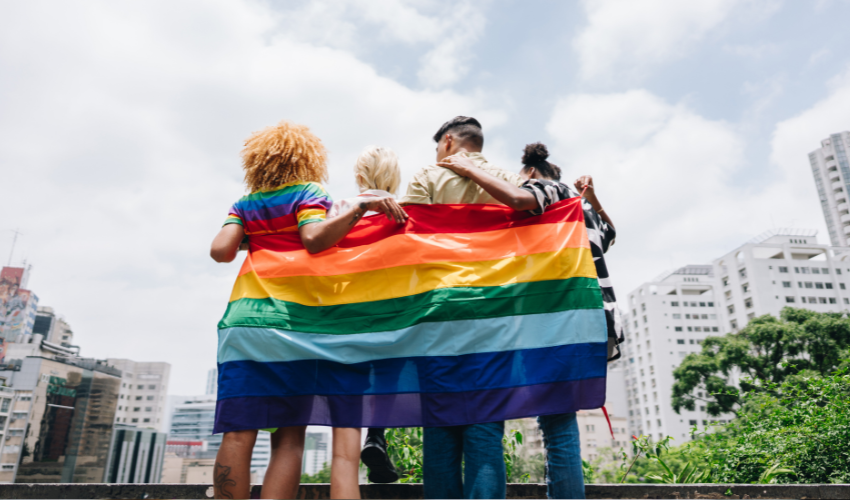 Group of people wrapped in an LGBT flag