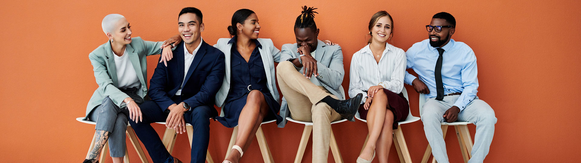 An diverse group of people sitting down smiling and laughing together.