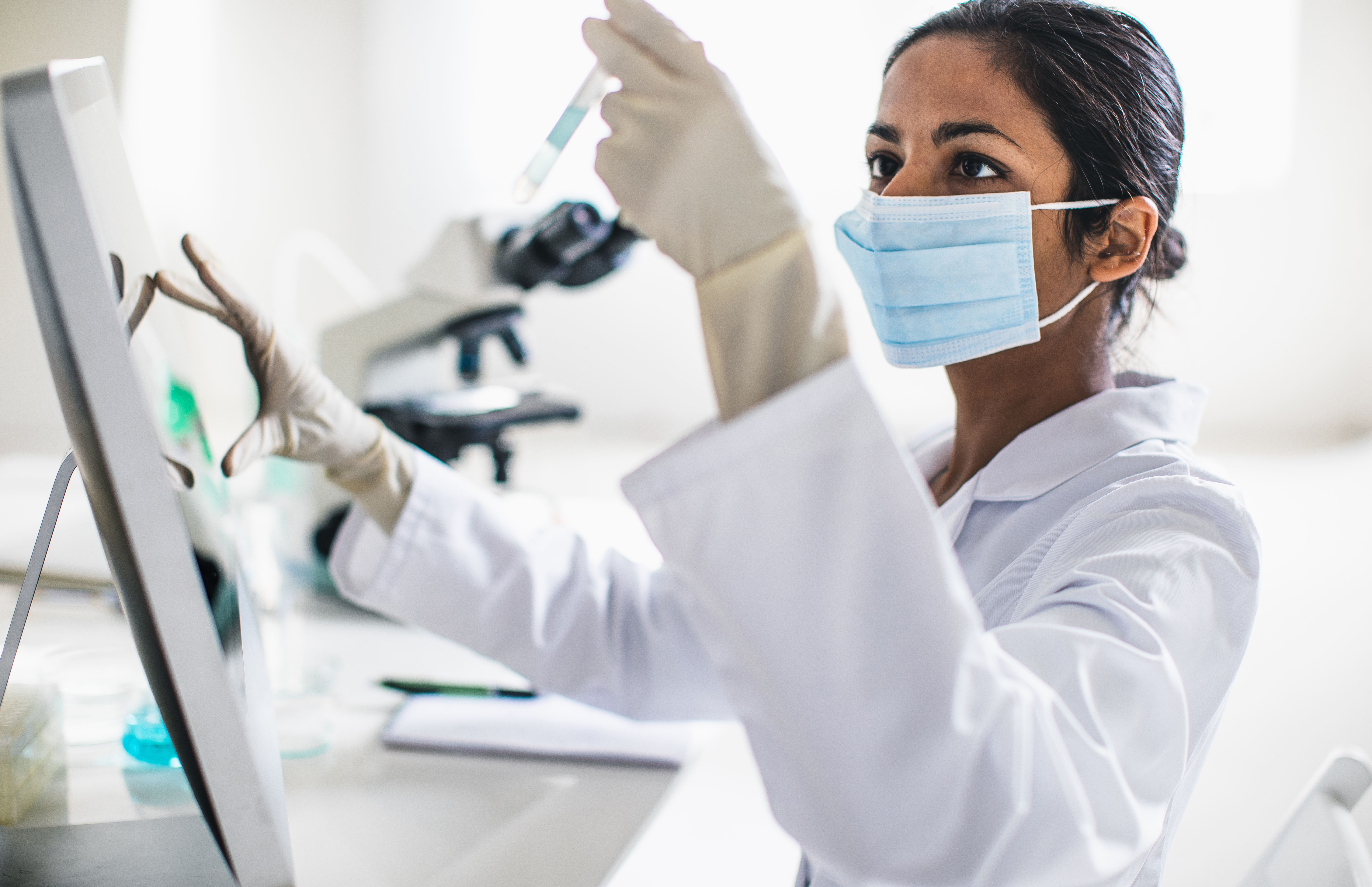 A lab technician looking at a sample in a test tube