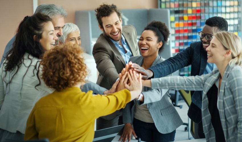 A diverse group of smiling professionals joining hands together in a celebratory high-five