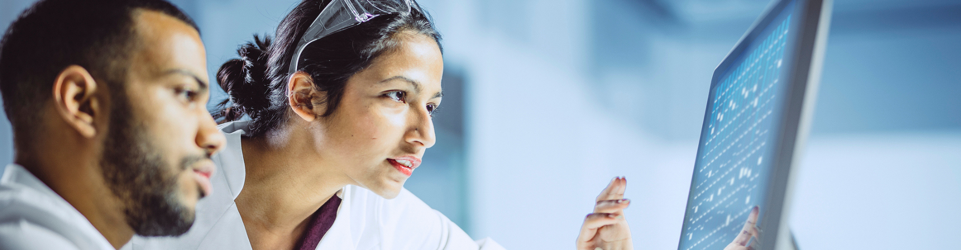 Two lab workers looking at a screen