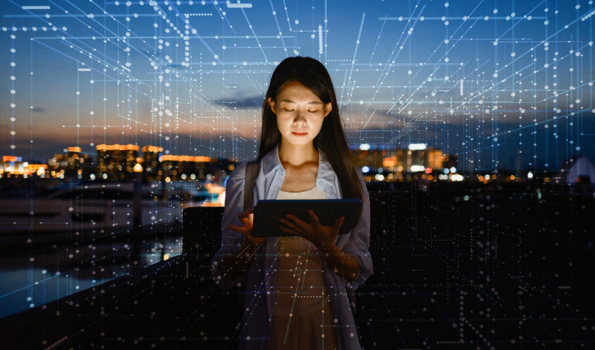 Woman using a tablet at night with a digital data overlay on a city background