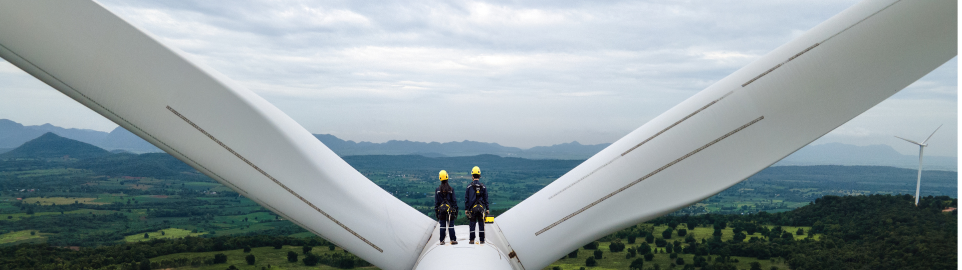 Two engineers standing at the top of a wind turbine