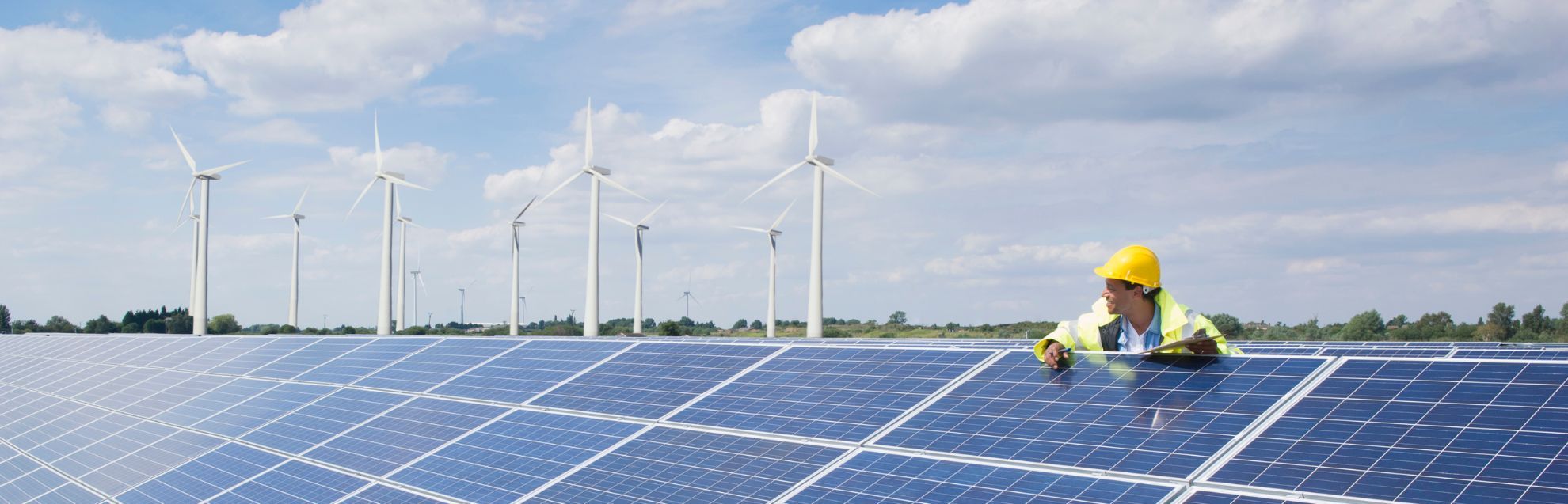A man in a hard hat checking solar panels on a roof