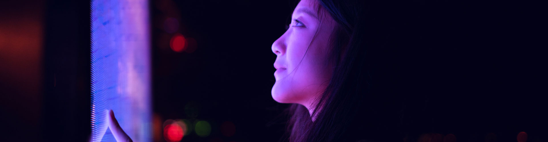 Young asian woman using touch screen in financial district at night 