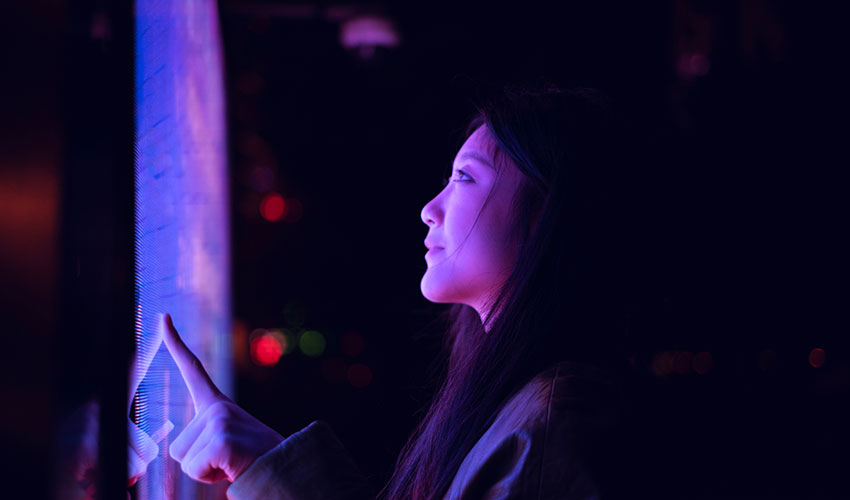 Young asian woman using touch screen in financial district at night
