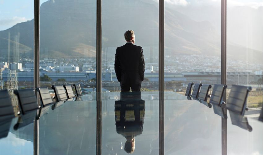 Man in boardroom looking out the window to a landscape view 