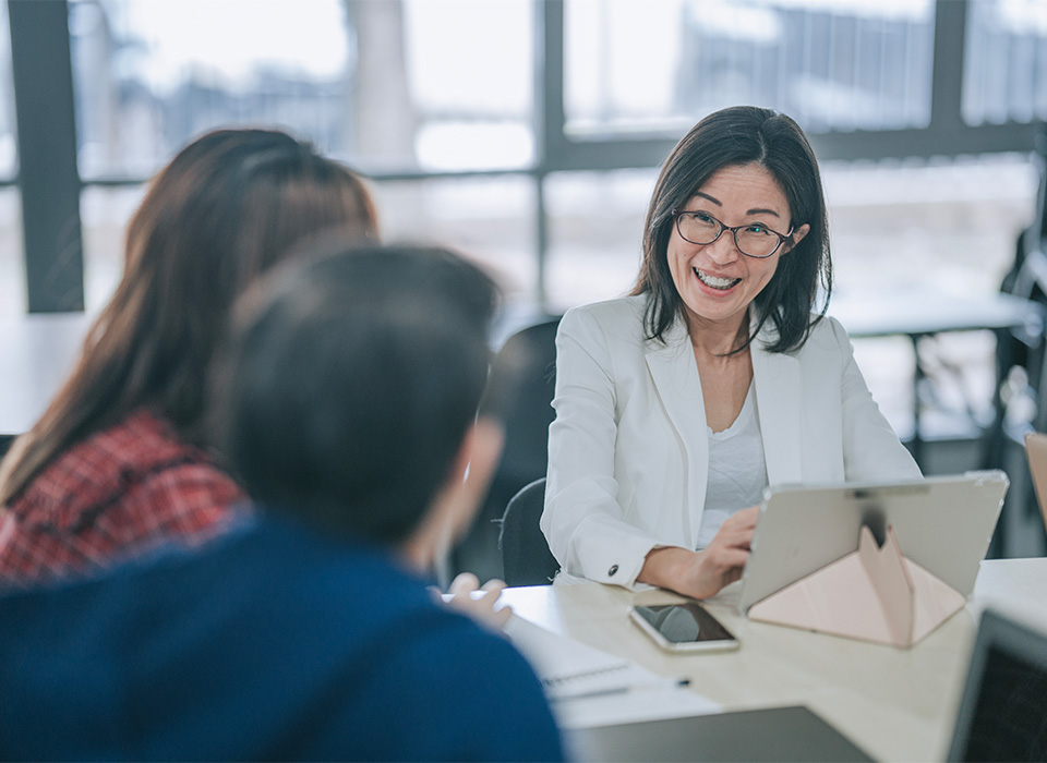 A woman smiling at her colleagues while working on a laptop