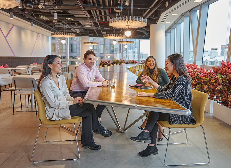 Four laughing and smiling colleagues sitting in an relaxed office environment