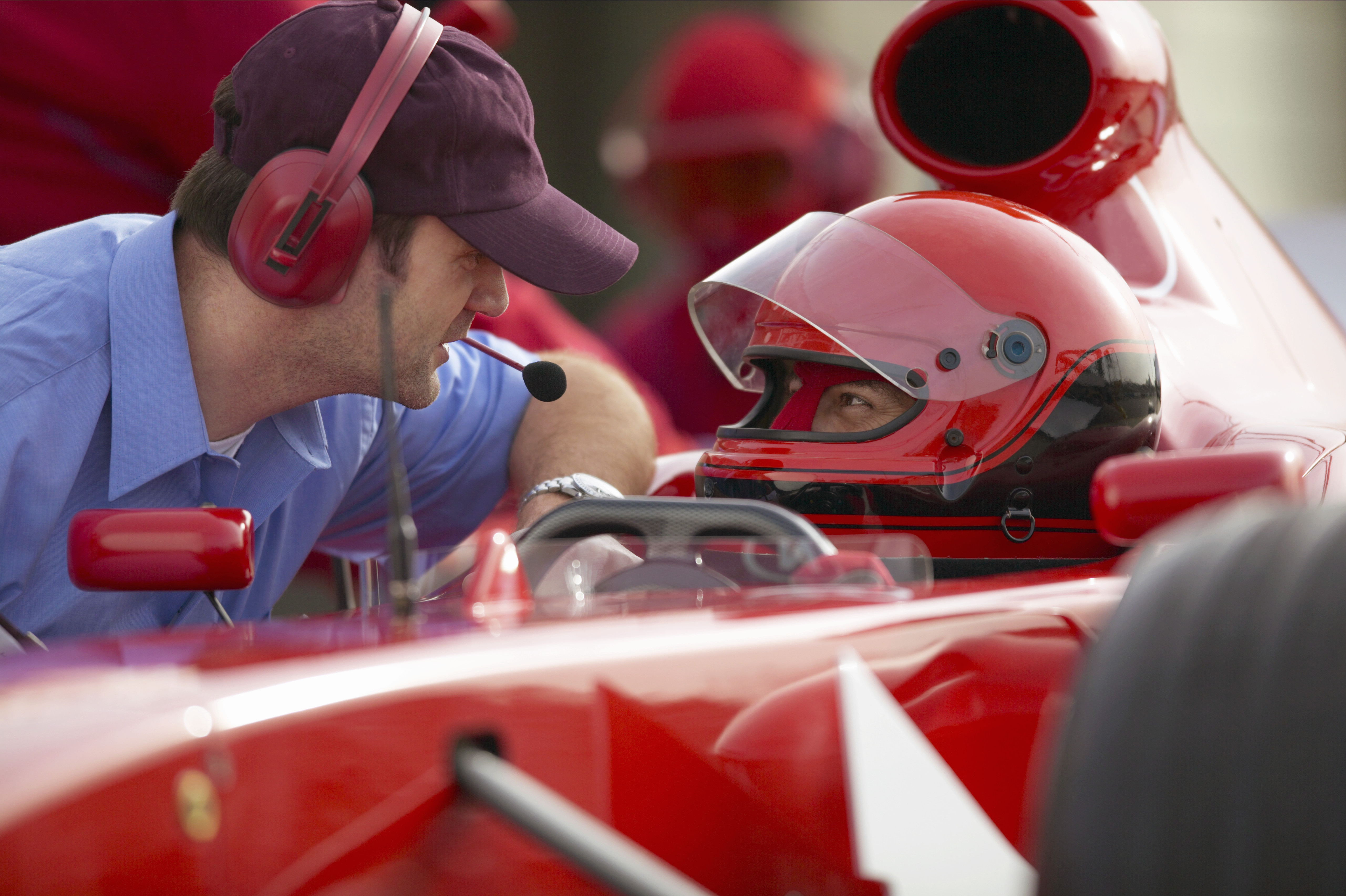 Racing driver talking with a man wearing a headset during a pit stop 