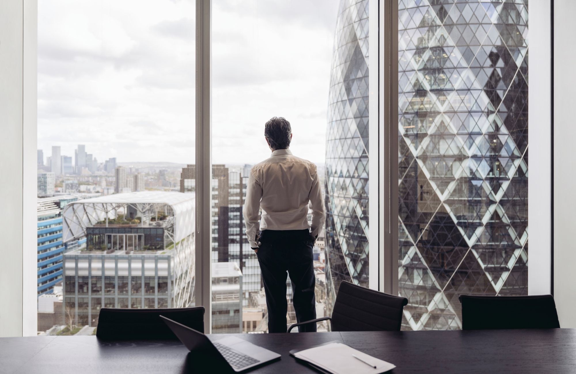 Businessman looking out window at London's financial district
