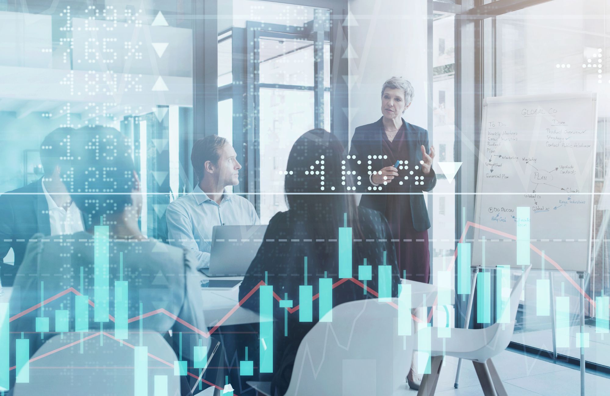 Businesspeople meeting in the boardroom superimposed over a graph showing the ups and downs of the stock market