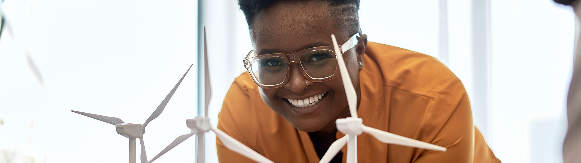 A smiling woman looking at model miniature wind turbines 