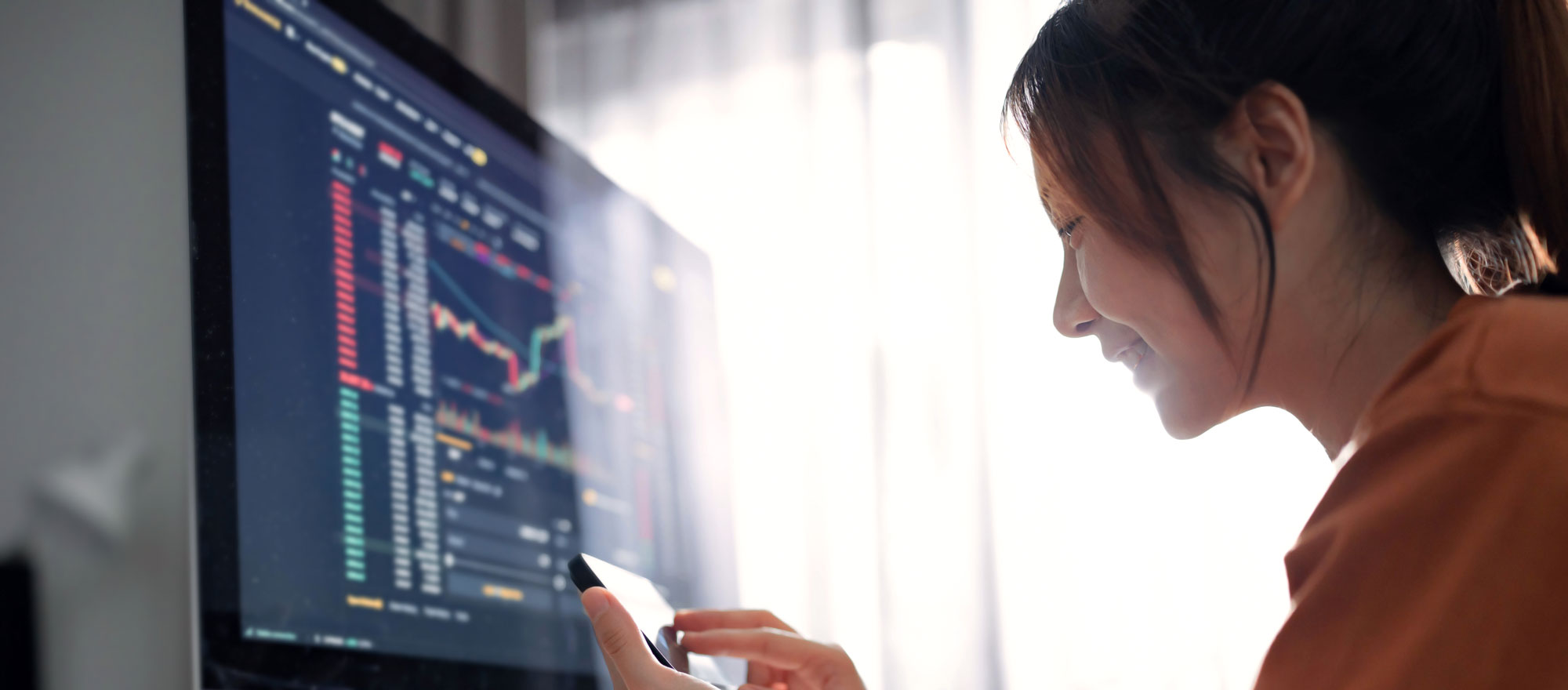 Woman using her smartphone in front of a computer