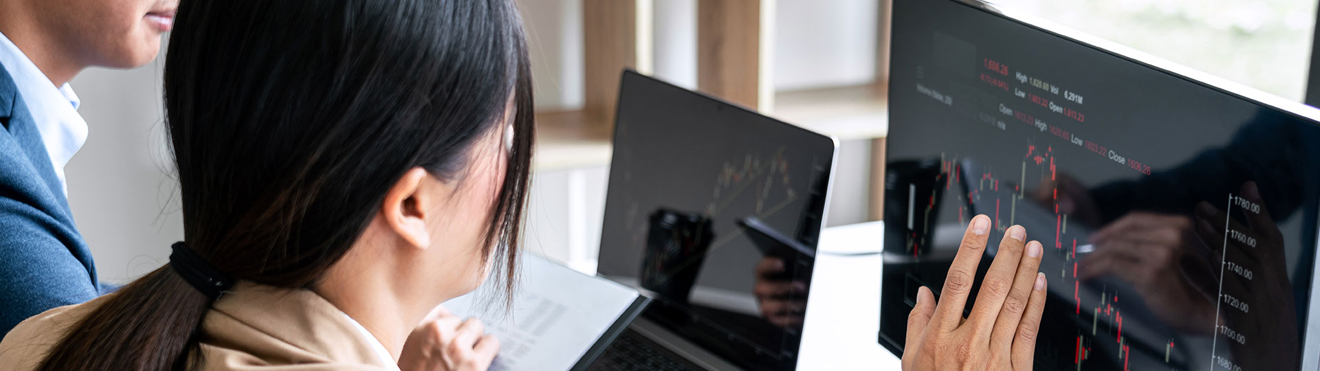 A woman touching a screen displaying stocks index prices