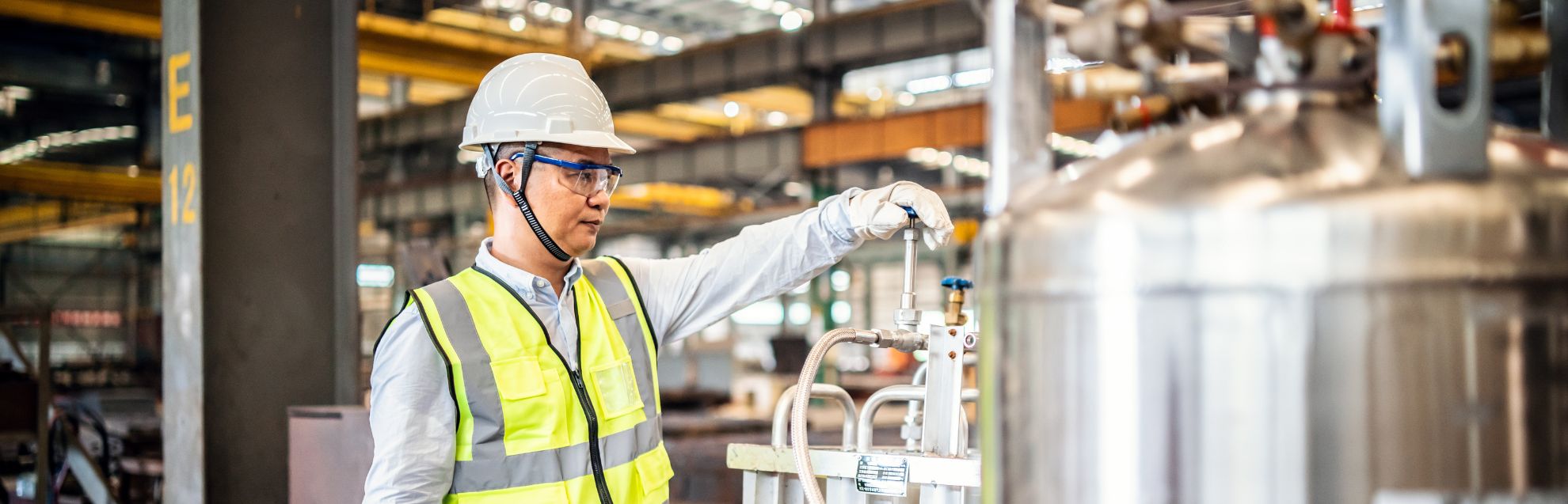 Asian worker operating a gas tank in a factory