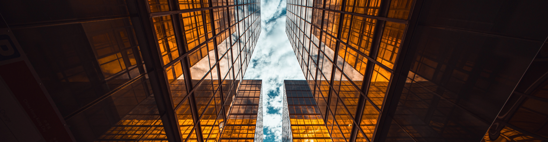 Low-angle view of golden glass skyscrapers reaching toward a cloudy blue sky