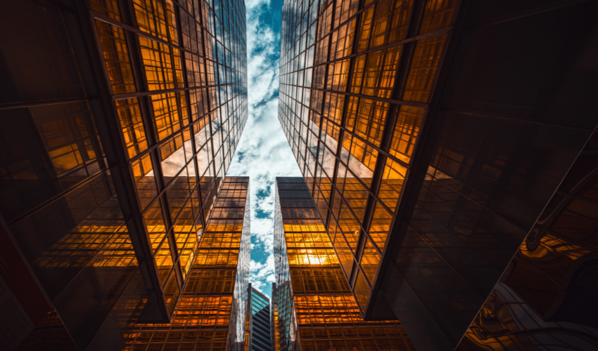 Low-angle view of golden glass skyscrapers reaching toward a cloudy blue sky