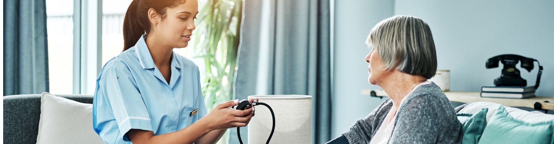 Nurse checking an elderly woman's blood pressure
