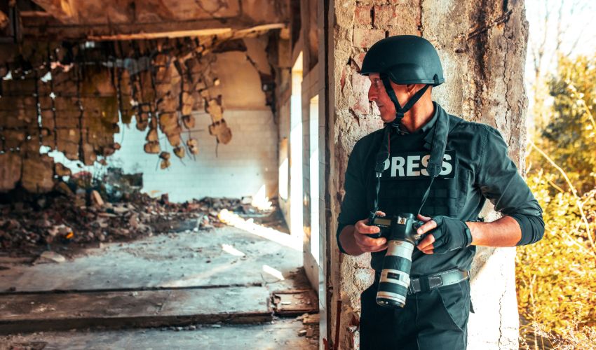 Man in press uniform taking photos in conflict
