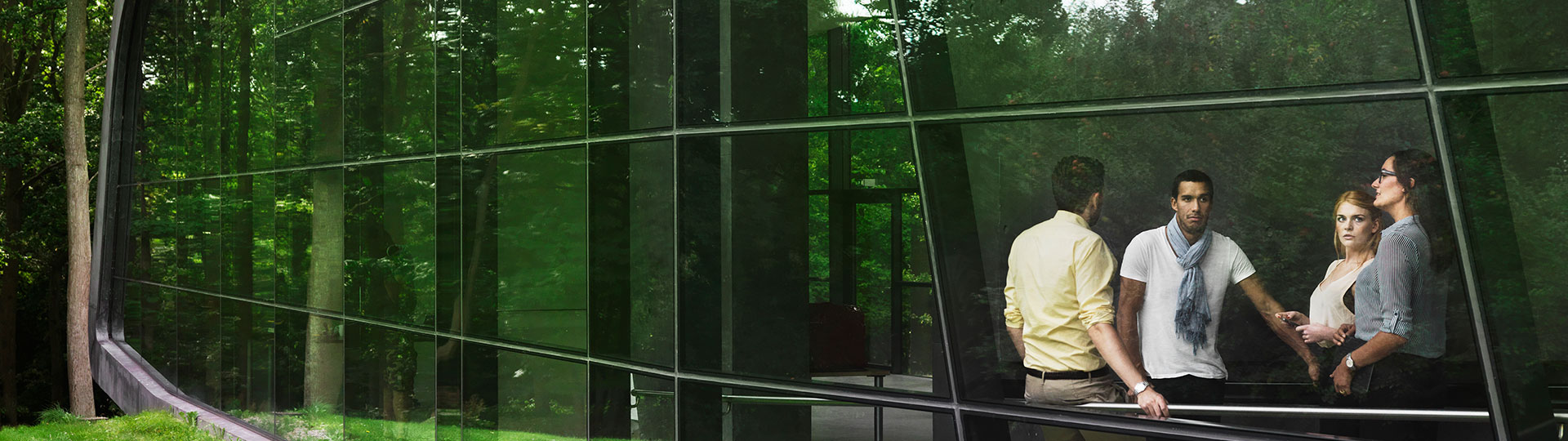 A group of people can be seen through a window with reflections of plants around them