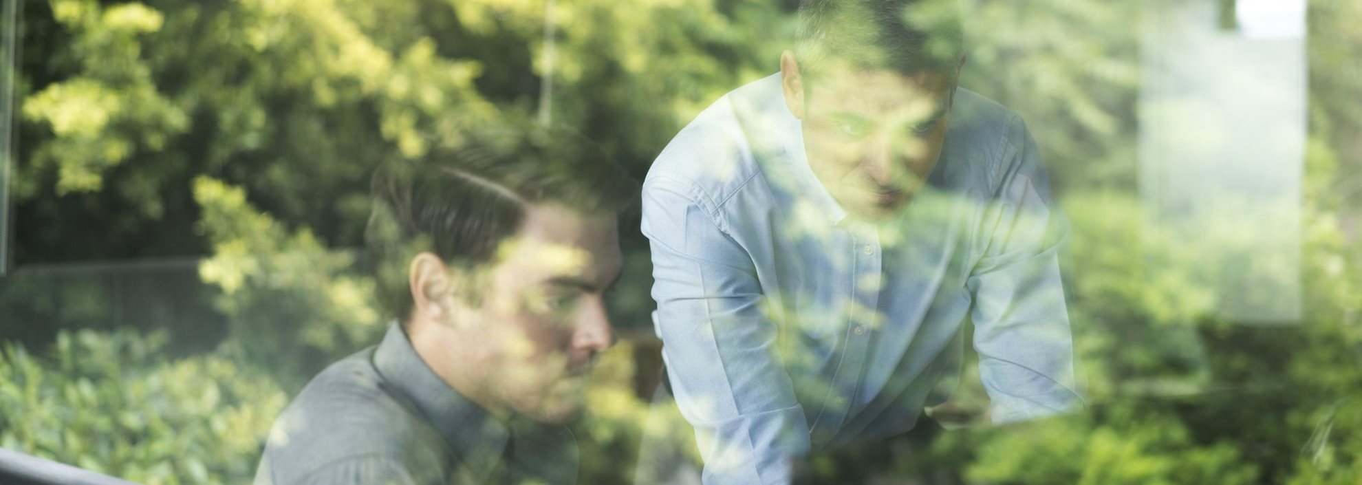 Two people looking at a hidden-from-view screen with trees in the background