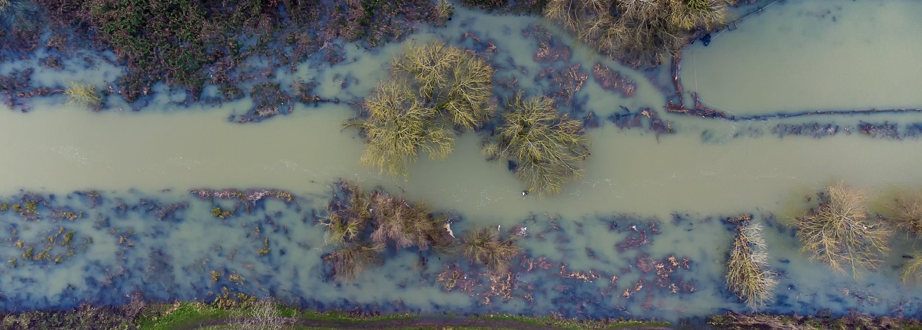 An aerial view of a muddy flooded river that has burst its banks