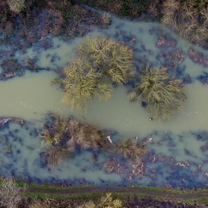 An aerial view of a muddy flooded river that has burst its banks