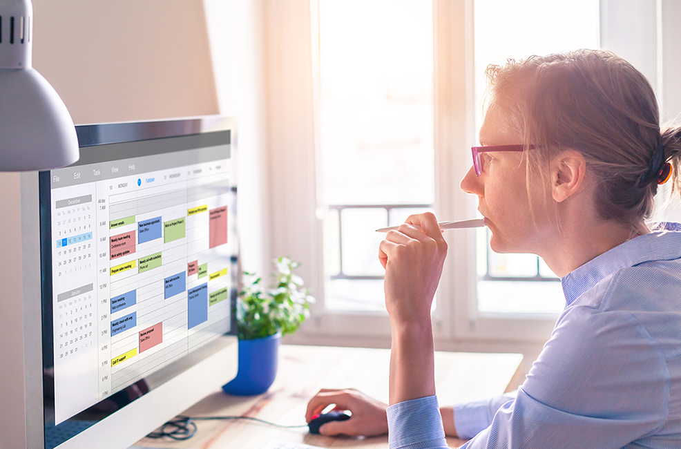 A thoughtful woman staring at the digital calendar on her computer screen