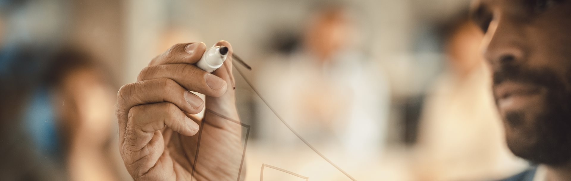 A man drawing a graph on a transparent wall
