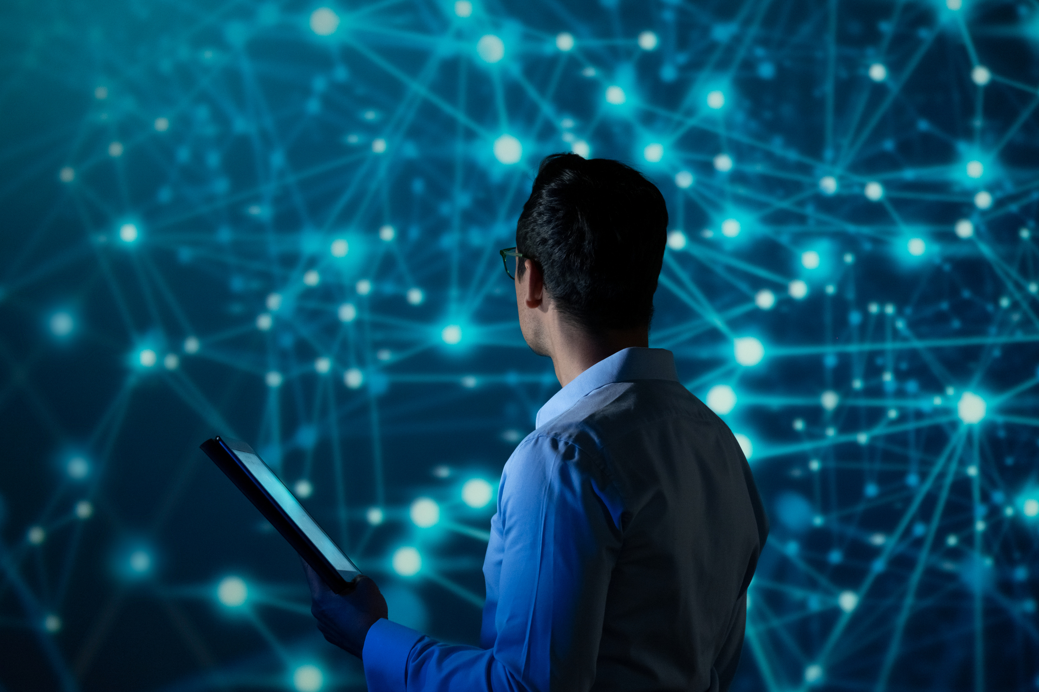 IT Specialist using tablet computer in front of big screen