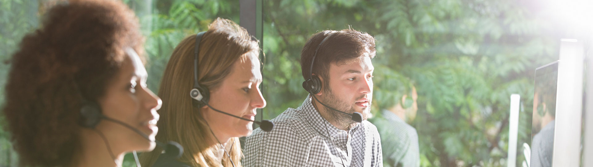 Three people wearing headsets working in a call centre