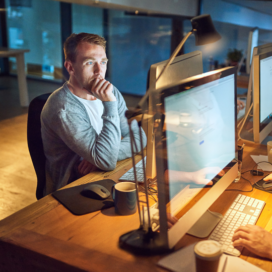A man deep in thought while looking at his computer